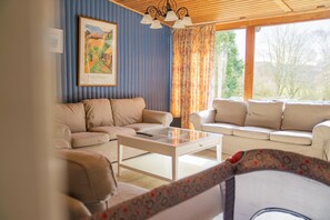 Relax in this stylish living room with a large window, beige sofa, and glass coffee table.