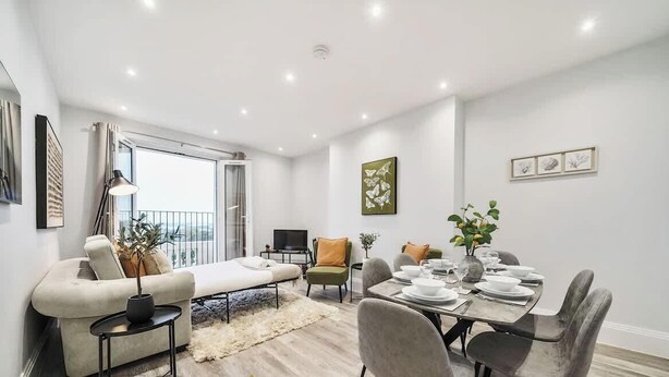 Een moderne woonkamer met een bank, een eettafel voor vier personen en een balkon met uitzicht.
