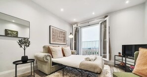 Une chambre moderne avec un lit, une télévision, un balcon et une vue sur la ville.