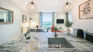 A modern kitchen with a marble countertop, two pendant lights, and a view to the outside. - Luxury 3BR Penthouse with Sea Views (Portsmouth)