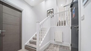 A modern interior with a wooden door, white staircase, and a gray wall. - Luxury 3BR Penthouse with Sea Views (Portsmouth)
