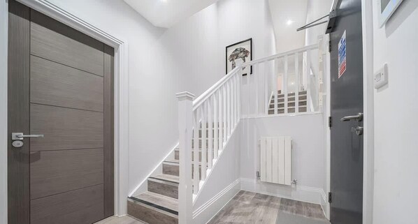 A modern interior with a wooden door, white staircase, and a gray wall. - Luxury 3BR Penthouse with Sea Views (Portsmouth)