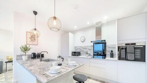 A modern kitchen with a marble countertop, a built-in oven, and a microwave. - Luxury 3BR Penthouse with Sea Views (Portsmouth)