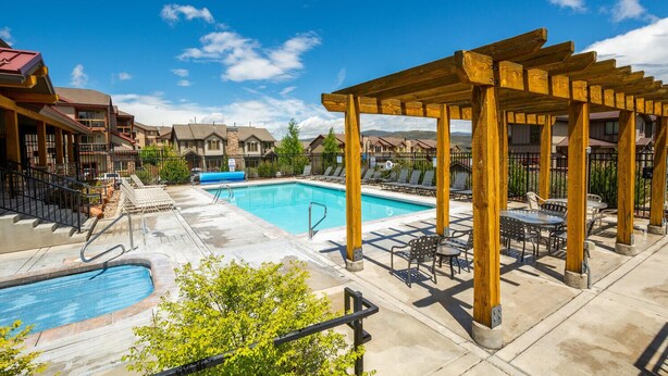 A pool area with a wooden pergola, lounge chairs, and a small pool.