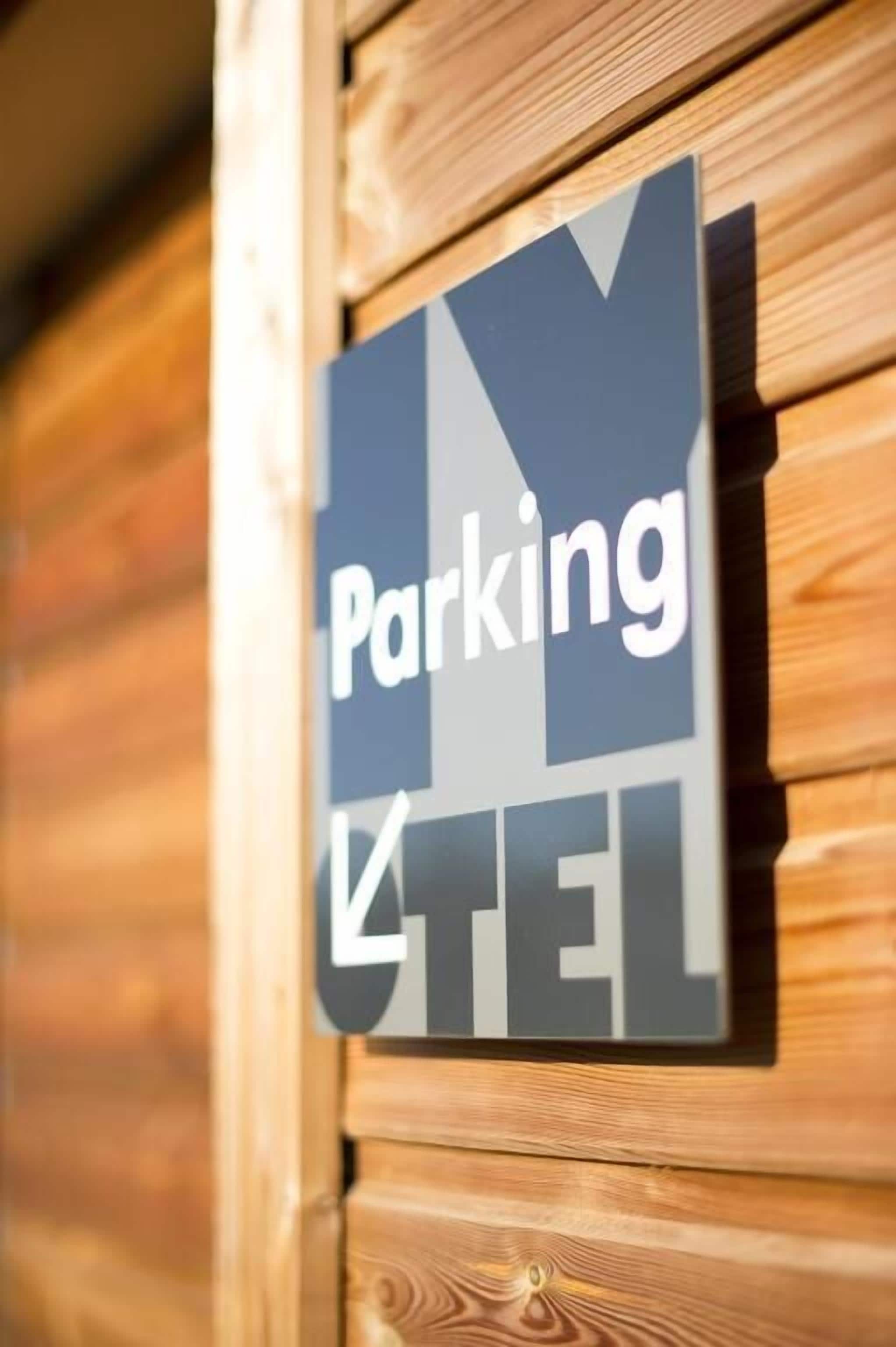 En skylt med orden ”Parkering” och ”TEL” på en trävägg.