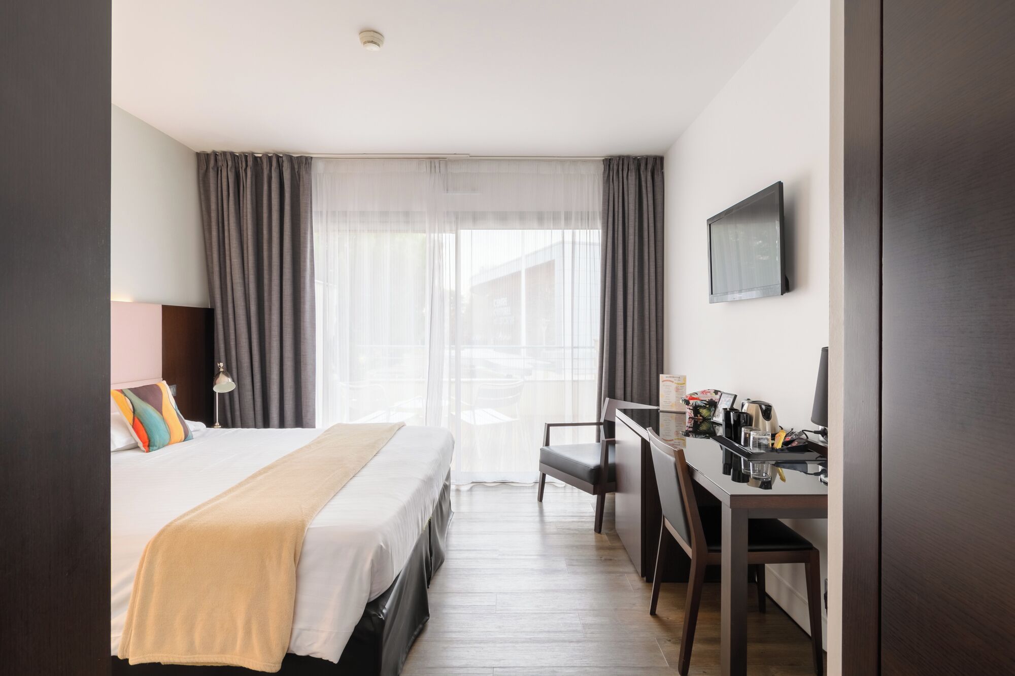 A hotel room with a bed, a desk, and a television.