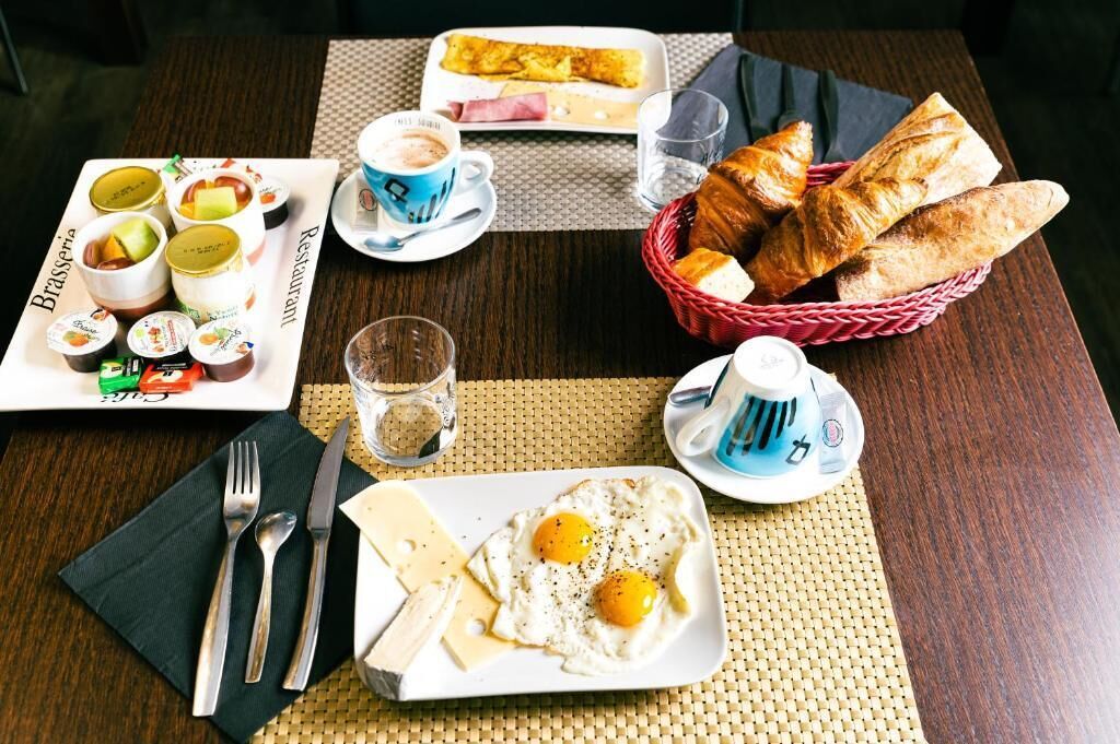 Una mesa con una variedad de alimentos para el desayuno, incluyendo huevos, pasteles y bebidas.