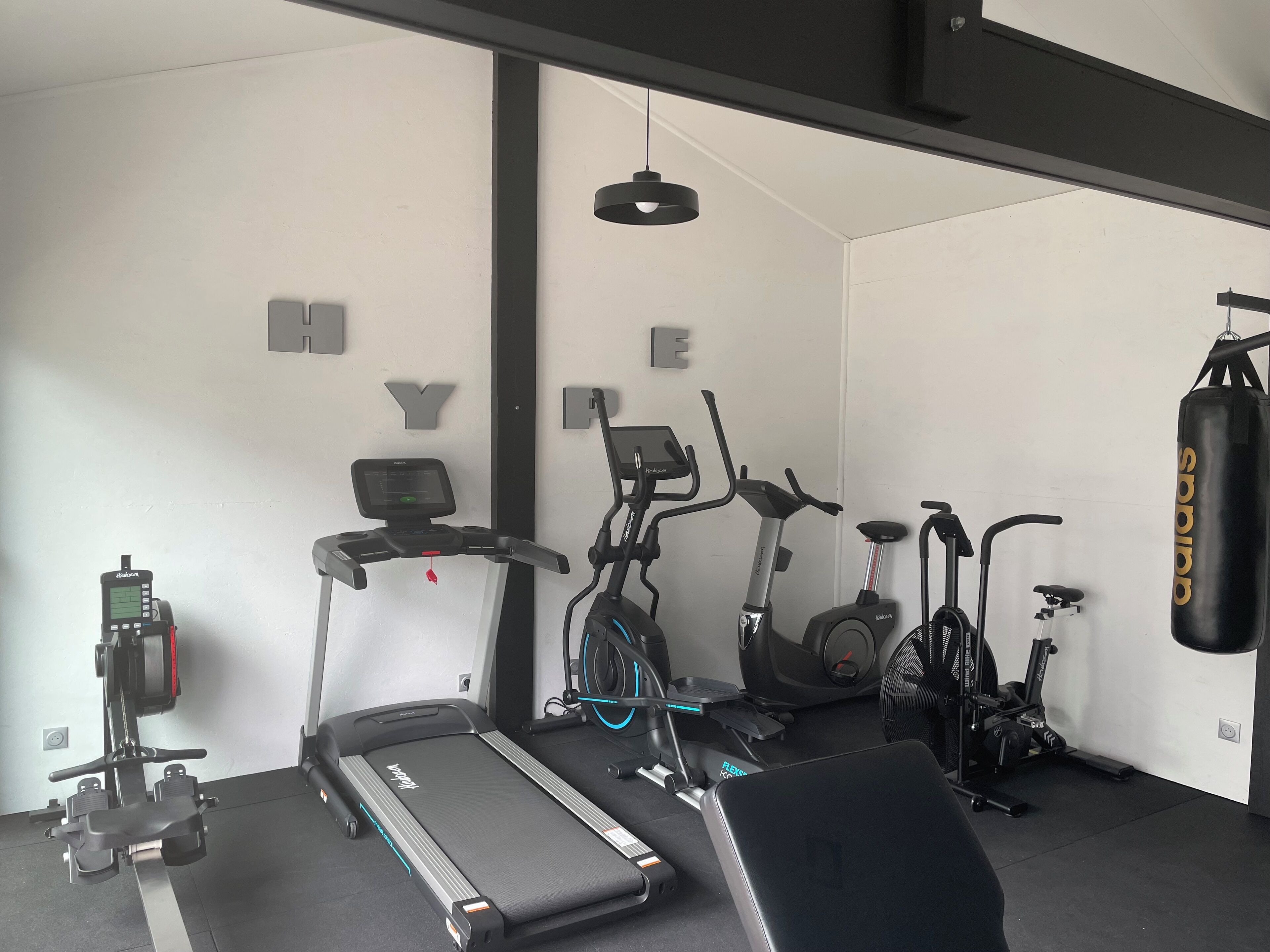A gym with a treadmill, stationary bikes, and a punching bag.