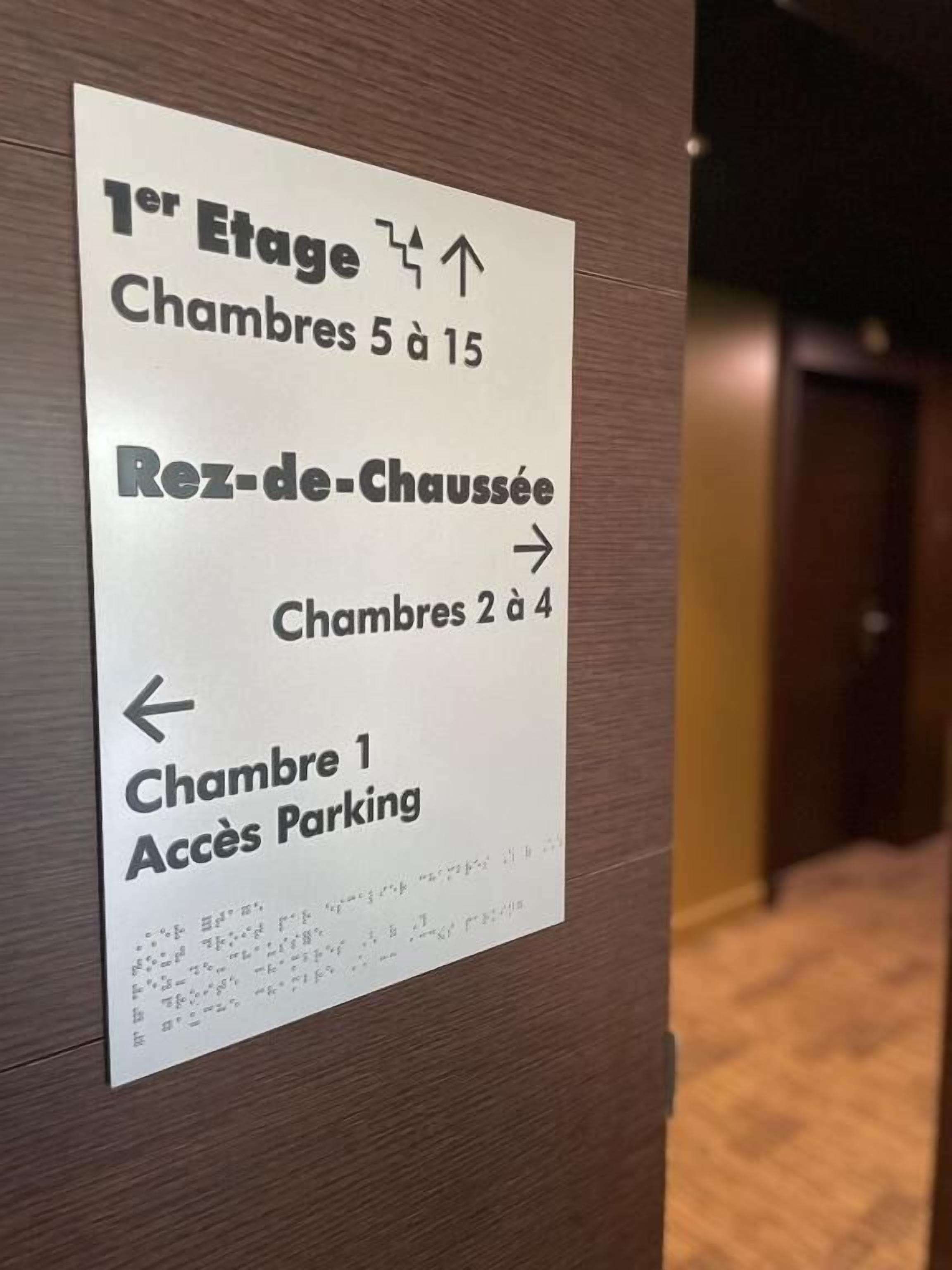 A directional sign for hotel rooms and parking.