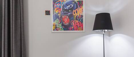 Une pièce avec un canapé gris, un lampadaire noir et un tableau abstrait aux couleurs vives accroché au mur.