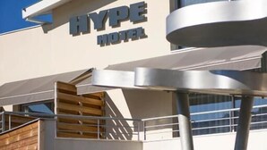 A modern hotel with a prominent sign reading "HYPE HOTEL". It features a two-story structure with a wooden facade on the lower level and large glass windows on the upper level. - Hype Hotel (Biscarrosse)