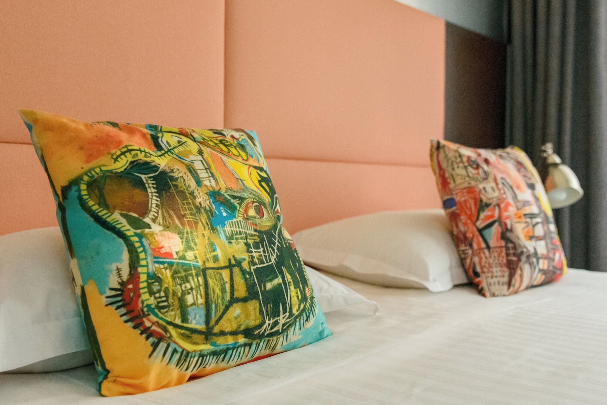 Ein Bett mit zwei bunten Kissen und einem weißen Kopfteil.