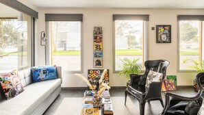 A modern living room with a sofa, black chairs, and a coffee table with books and a vase. - Hype Hotel (Biscarrosse)