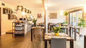 A modern dining area with wooden tables, chairs, and a central serving station. - Hype Hotel (Biscarrosse)