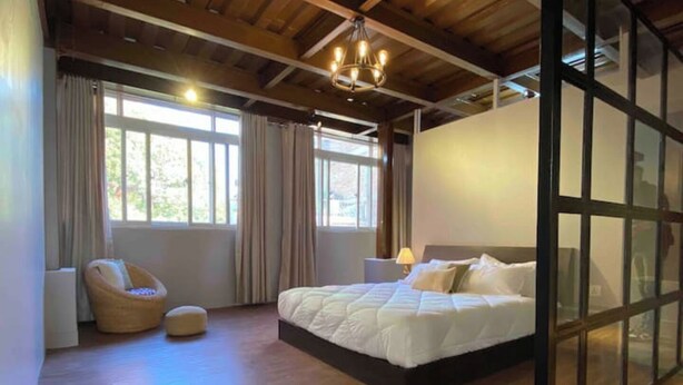 Un dormitorio con una cama grande, una silla y un separador de vidrio.