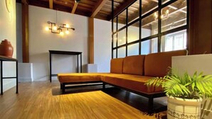 Una sala de estar moderna con piso de madera, un sofá modular, una mesita y una planta en maceta.