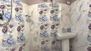 Un baño con patrones de azulejos florales, un lavabo blanco y una zona de ducha.