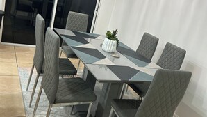 Ein Essbereich mit Tisch und Stühlen, einer kleinen Topfpflanze und einem gemusterten Teppich.