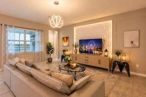 Un soggiorno moderno con un divano, TV, illuminazione decorativa e un dipinto con vista sulla città.