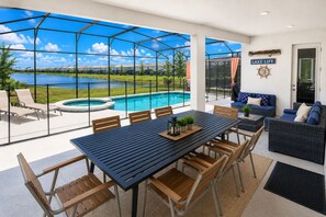 Un'area esterna coperta con piscina, un tavolo da pranzo con sedie e un divano.