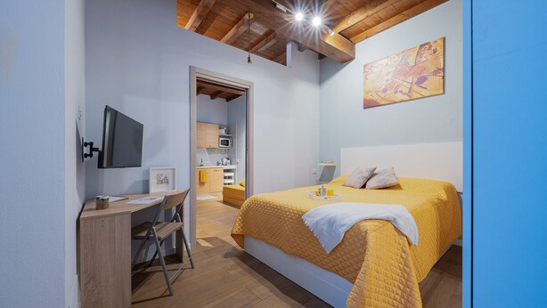 Een slaapkamer met een bed, een bureau en een kitchenette.