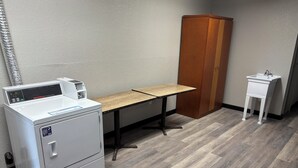 Ein Waschraum mit Waschmaschine, Holztisch, Schrank und Spüle.