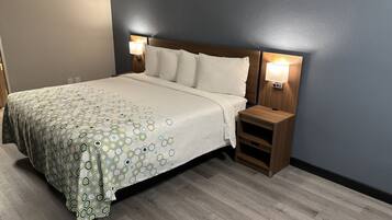 A neatly made bed with a patterned bedspread, two bedside lamps, and a wooden nightstand with a shelf.