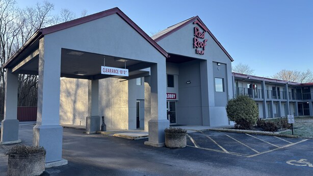 Un hôtel Red Roof Inn doté d’une entrée abritée, d’une enseigne au-dessus du hall d’entrée et d’un panneau indiquant « Stationnement interdit ».