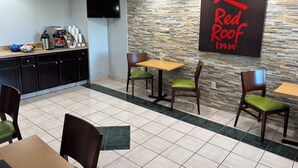 Un espace repas de l’hôtel Red Roof Inn, avec un mur en pierre, un téléviseur à écran plat et un comptoir de buffet.