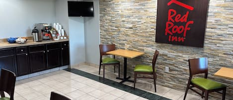 A Red Roof Inn dining area with a stone wall, a flat-screen TV, and a buffet counter.