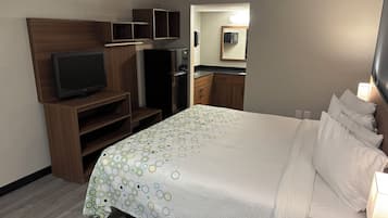 Een hotelkamer met een bed, een televisie, een kledingkast en een badkamer, zichtbaar door een geopende deur.
