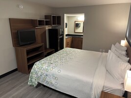 Habitación de hotel con cama, televisión, armario y baño visible a través de una puerta abierta.