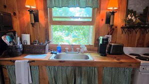 Une cuisine équipée d’un plan de travail en bois, d’un évier, d’une bouilloire et d’une cuisinière.