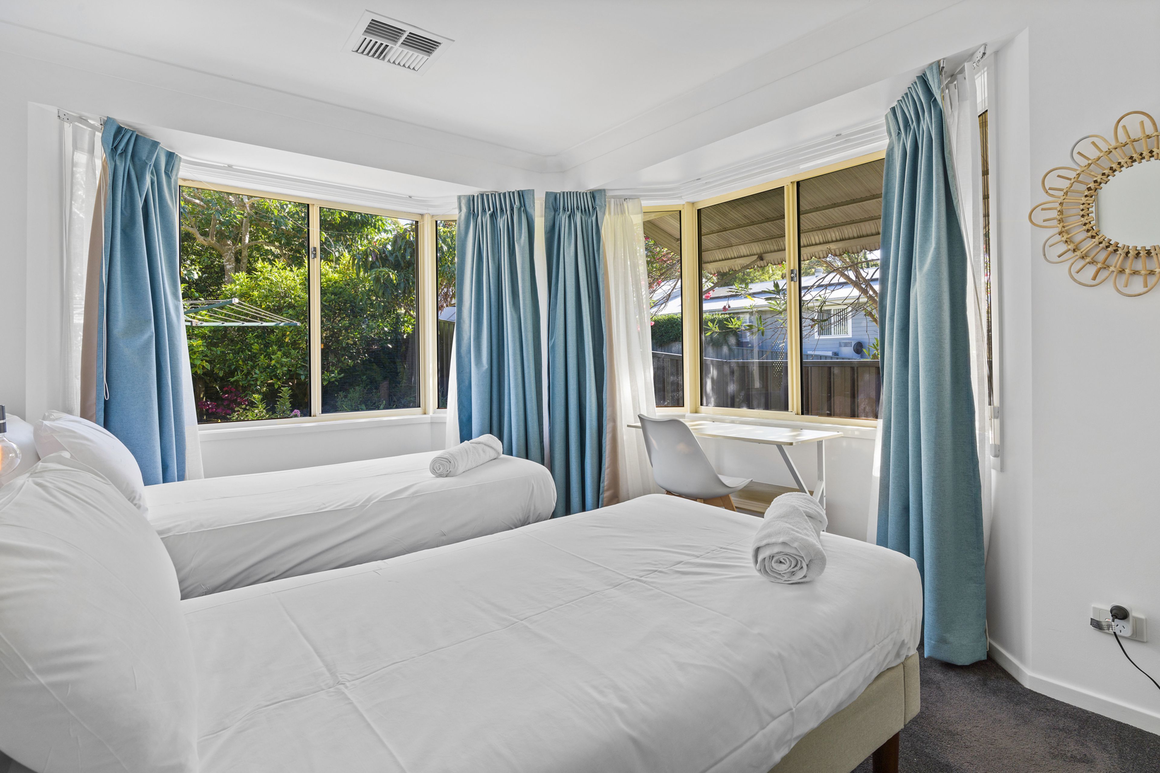 Un dormitorio con dos camas, un escritorio y una ventana con cortinas.