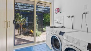 Een wasserette met een wasmachine, een droogrek en een douchegedeelte.