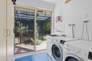 A laundry room with a washing machine, a drying rack, and a shower area. - Waterfront Paradise Lodge Brightwaters (Brightwaters)