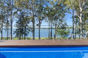 A pool with a view of a lake and trees.
