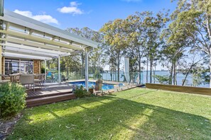 A covered outdoor area with a pool, seating, and a view of the water. - Waterfront Paradise Lodge Brightwaters (Brightwaters)