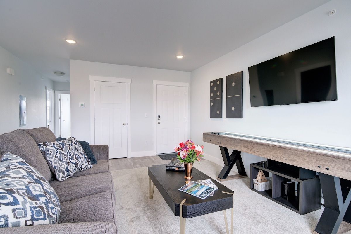 A modern living room with a sofa, coffee table, and a flat-screen TV mounted on the wall.