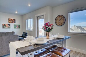 A dining area with a table set for two, a clock on the wall, and artwork on the walls. - NEW Mountain Game Room Getaway (Bozeman)
