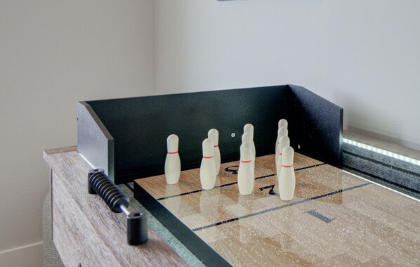 A foosball table with six white bowling pins and a black table corner. - NEW Mountain Game Room Getaway (Bozeman)