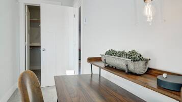 A dining area with a wooden table, a bench, a potted plant, and a hanging light fixture.