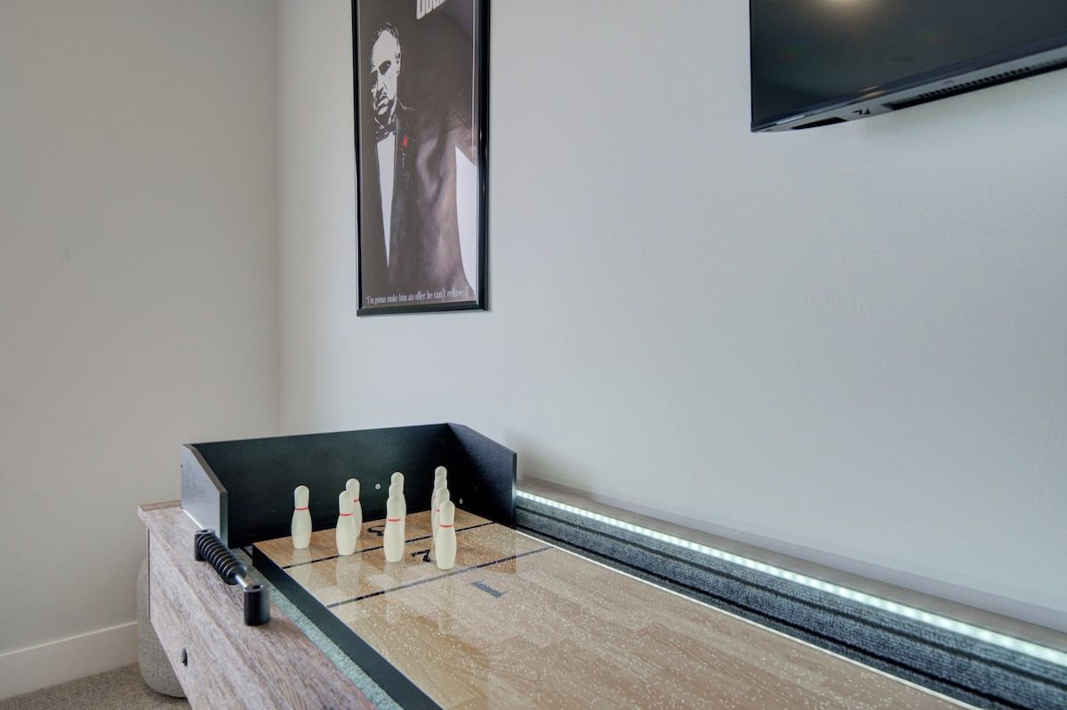 A foosball table in a room with a framed picture on the wall and a flat-screen TV mounted above it.
