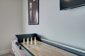Una mesa de fútbol de mesa en una habitación con un cuadro en la pared y un televisor de pantalla plana montado encima.