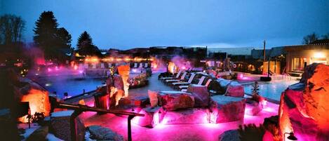 A heated outdoor pool area with seating and a stone structure.