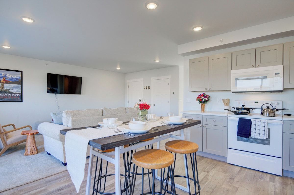 Una cocina moderna con comedor, muebles blancos, microondas y estufa.