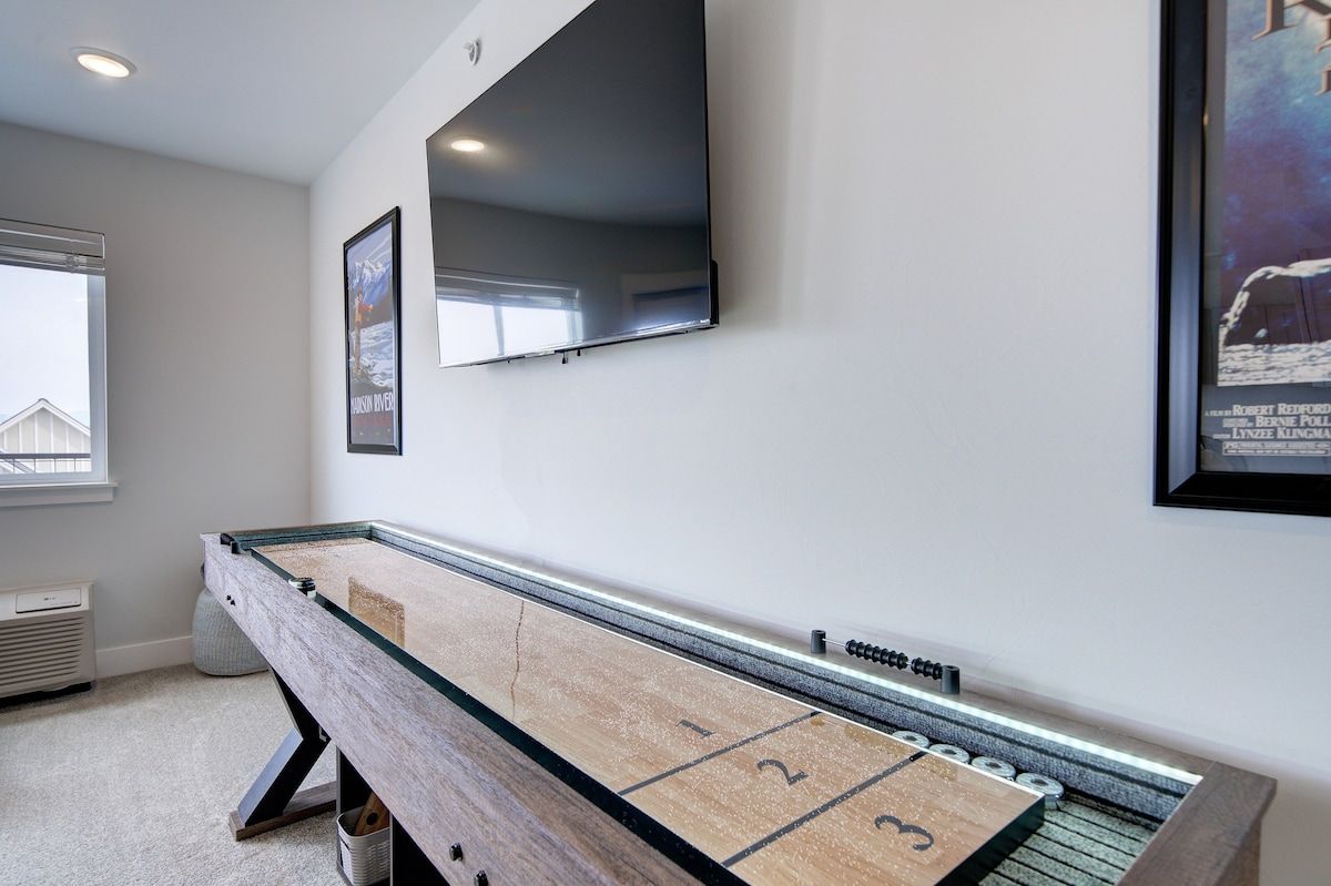 Une table de billard avec un mur miroitant au-dessus, un tableau encadré et une fenêtre donnant sur un immeuble.