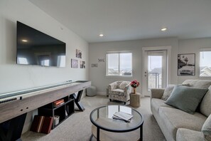 A living room with a flat-screen TV, a pool table, a sofa, and a coffee table. - NEW Mountain Views | Hot Springs | Truck Stop (Bozeman)