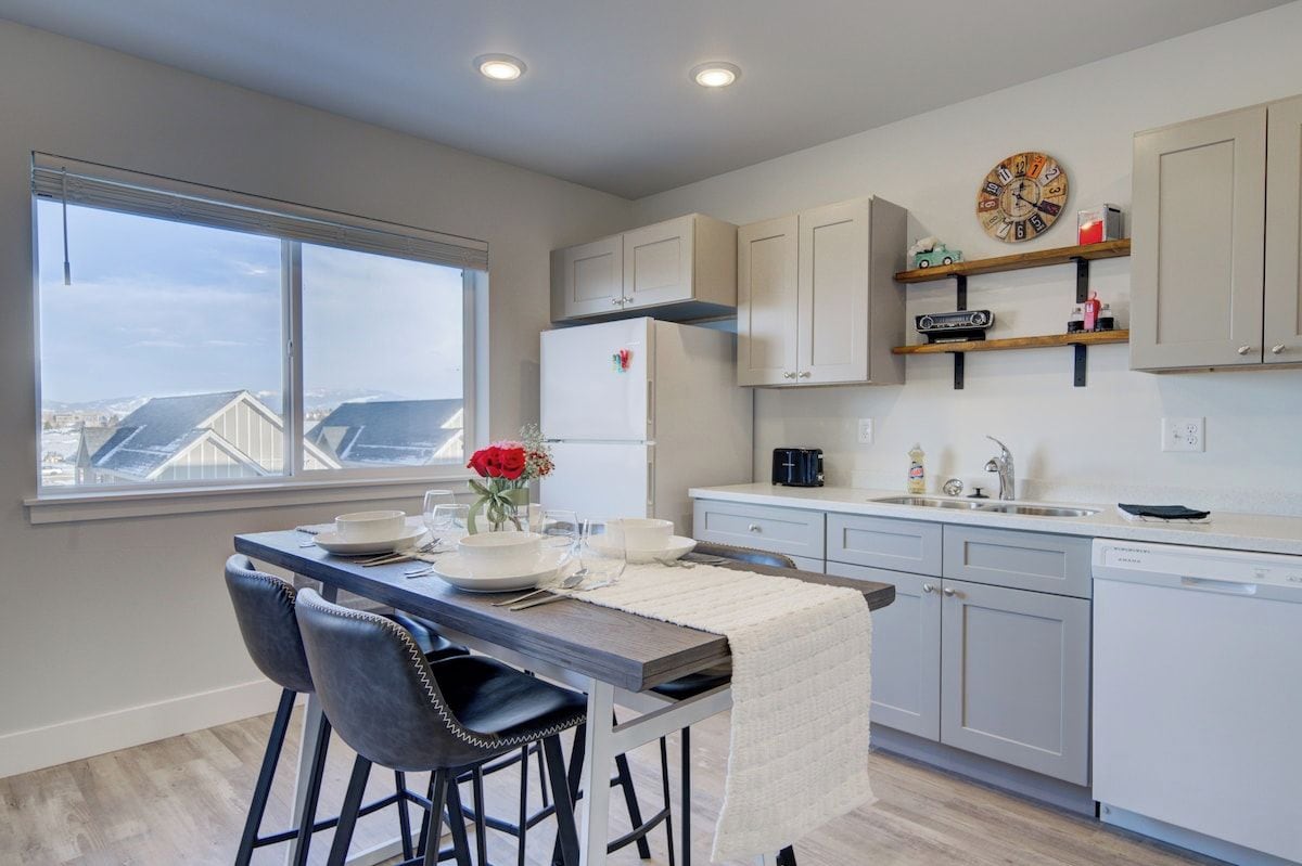A modern kitchen with white cabinets, a built-in oven, and a window overlooking a cityscape.