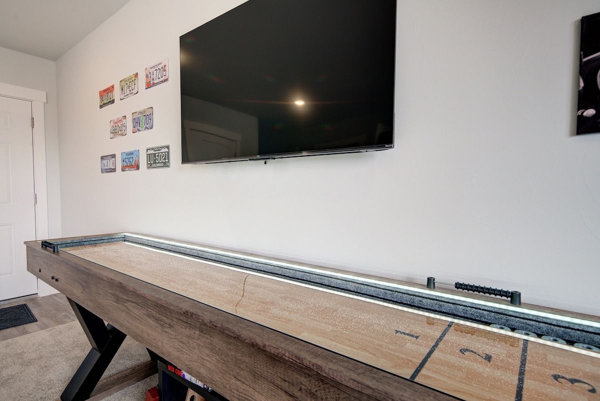 Ein Billardtisch mit einem darüber befestigten Fernseher und mehreren an der Wand hängenden Nummernschildern.